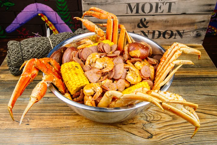 Crab legs and shrimp piled high with corn, sausage, and potatoes